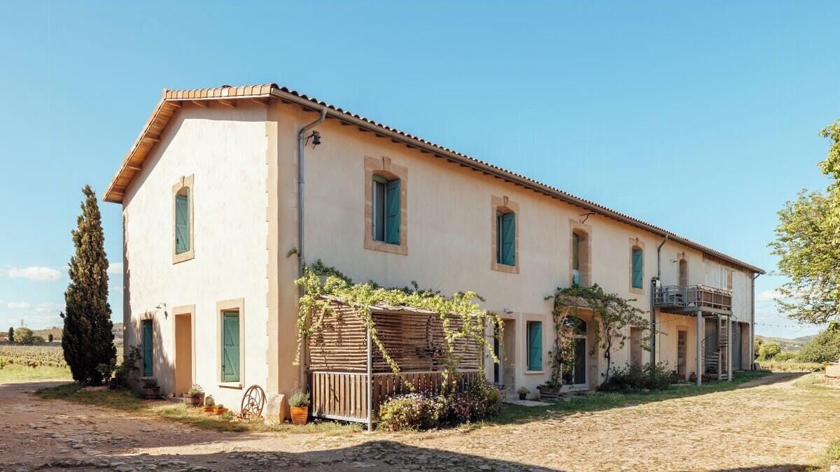 A two-story building with a tiled roof, a wooden fence, and a gravel driveway.