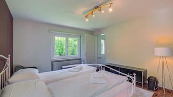 Une chambre avec deux lits, une fenêtre, un radiateur, une table de chevet, une lampe et un miroir.