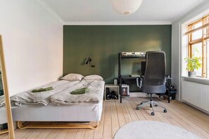 A bedroom with a bed, desk, chair, and a radiator.