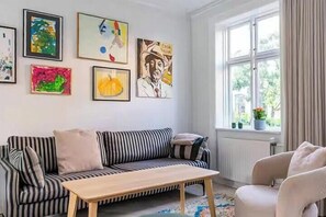 A living room with a striped sofa, a wooden coffee table, and a window with curtains.
