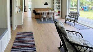 A spacious room with a wooden floor, a bench, a dining table with chairs, and a view of the outdoors. - Idyllic view to the fjord from home (Jægerspris)