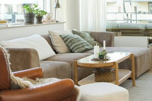 Ein gemütliches Wohnzimmer mit einer Couch, einem Sessel und einem kleinen Tisch mit einer Kerze.