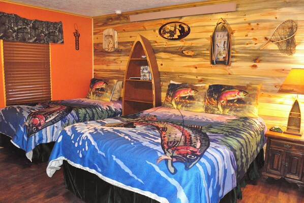 Ein Zimmer mit zwei Betten, einer Holzwand, einem Regal und einer Lampe.