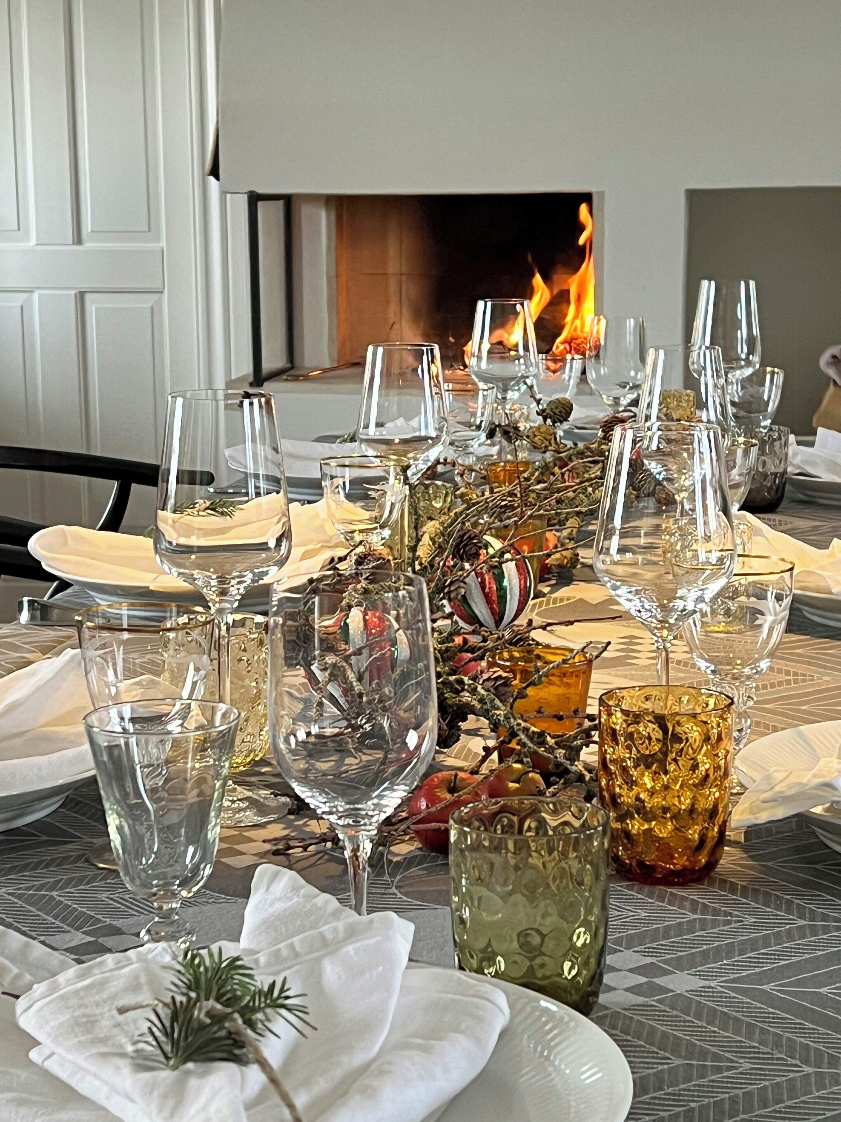 Une table mise pour le dîner, avec des verres à vin, des assiettes et un centre de table décoratif.