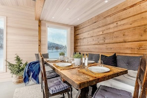 Ein Holzespeisesaal mit Stühlen, ein Blick auf eine verschneite Landschaft durch ein Fenster und eine Pflanze auf dem Boden.