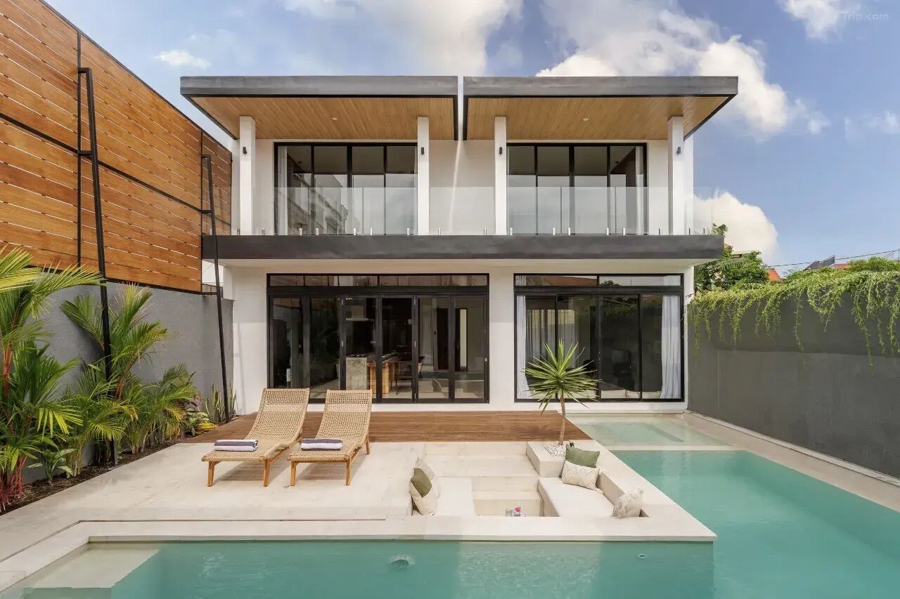 A modern two-story house with a swimming pool, outdoor seating, and lush greenery.