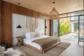 Un dormitorio moderno con una cama grande, paneles de madera, una lámpara colgante y vista a una piscina.