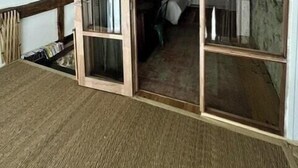 Ein Zimmer mit einer großen Glasschiebetür, die zum Schlafbereich führt, einer Holzbalkendecke und einem sichtbaren Bett.