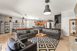 Ein modernes Wohnzimmer mit einem grauen Ecksofa, einem Holztisch und gemusterten Teppichen.