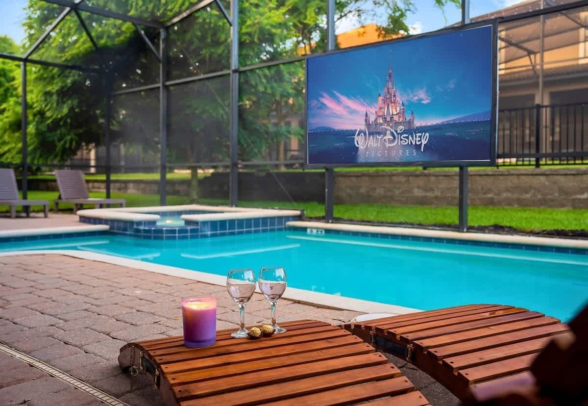 Ein Poolbereich mit Holzliegen, einer Kerze und zwei Gläsern auf einem Tisch.