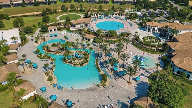 A resort with multiple swimming pools, palm trees, and a well-maintained landscape. - 9BR Themed Close to Disney World! Movie Theatre! (Four Corners)