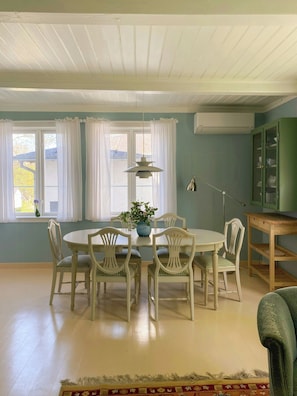A dining room with a round table, four chairs, a vase with flowers, and a lamp.