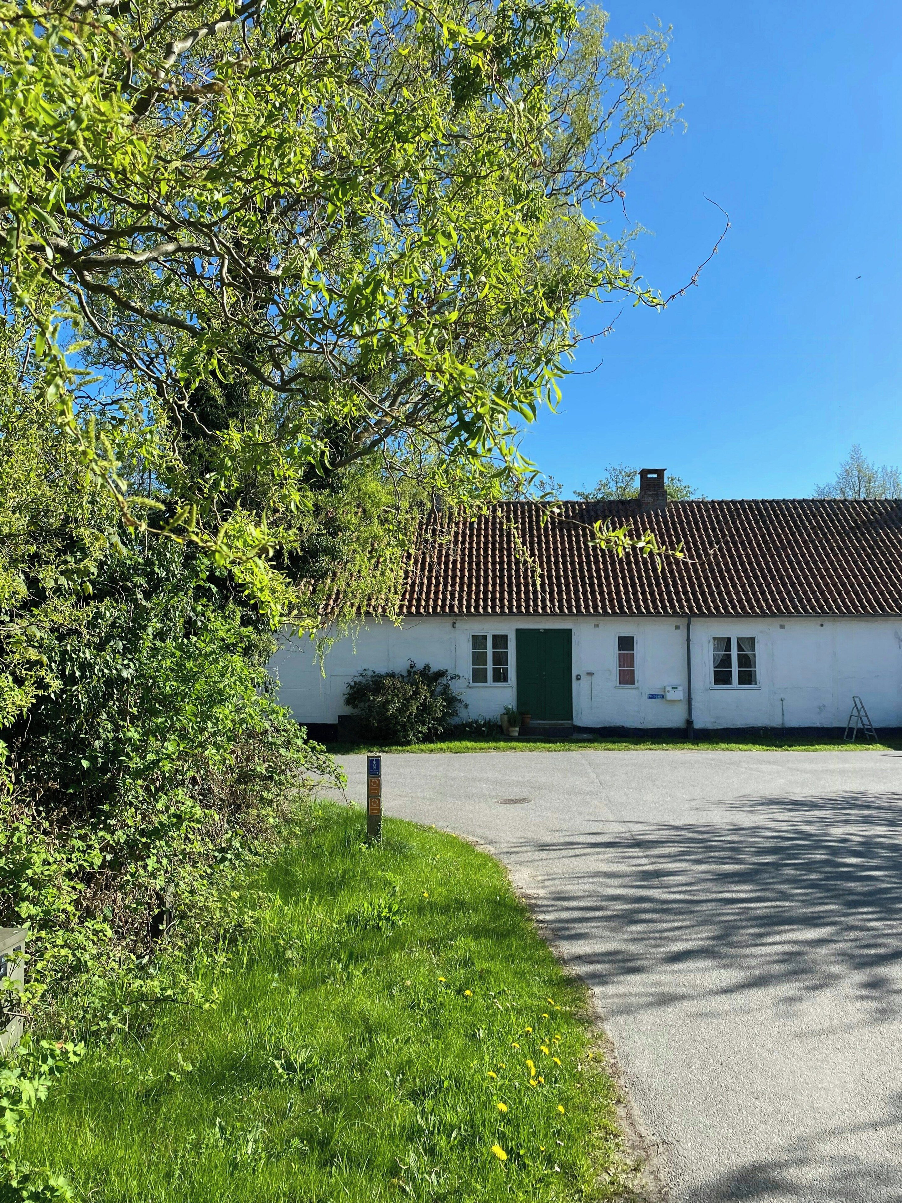 Un bâtiment blanc avec un toit en tuiles, une porte verte et une allée pavée.