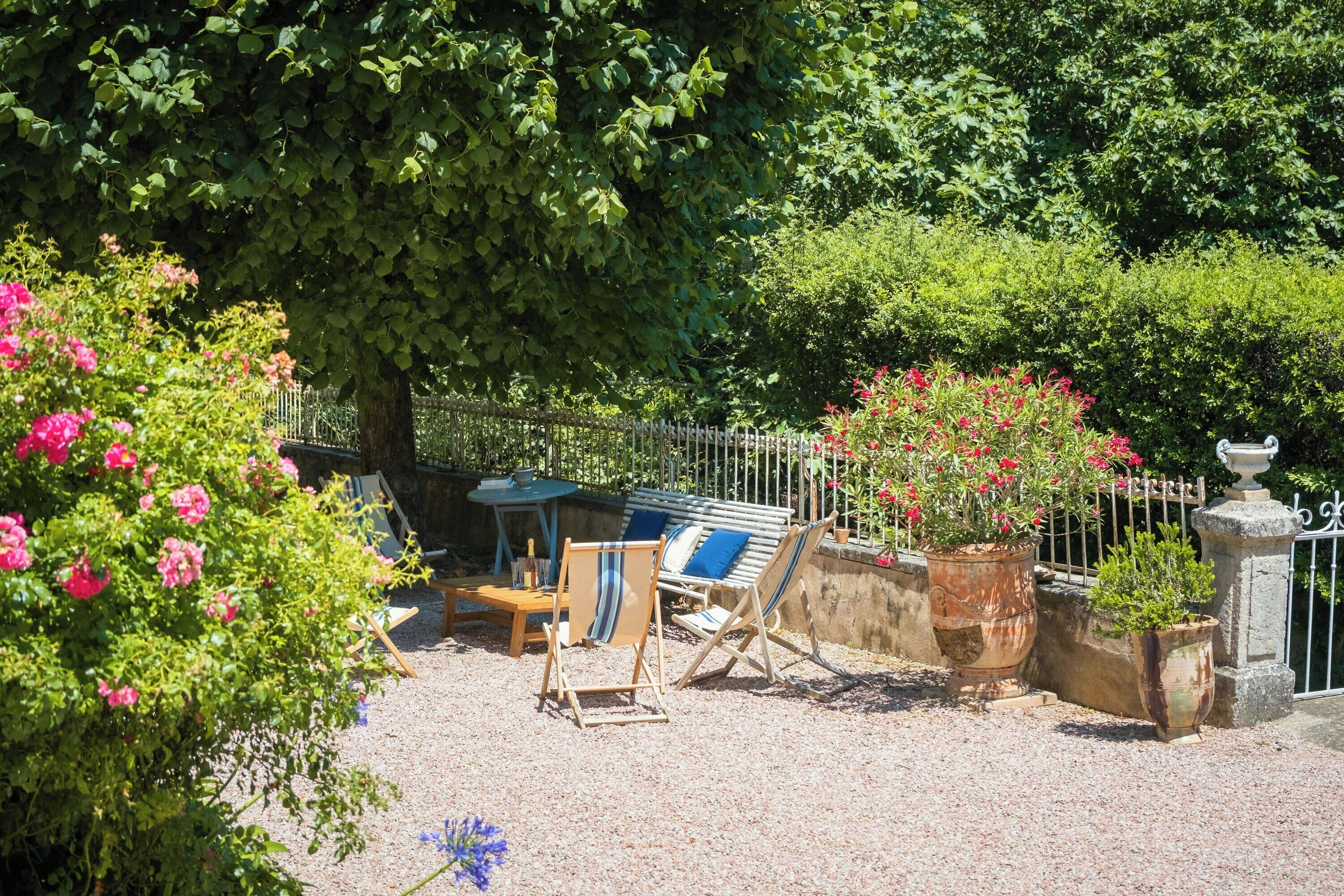 Um jardim com área de estar, cerca e vasos de plantas.