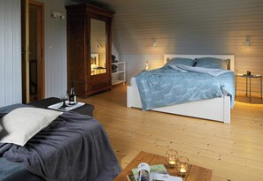 A bedroom with a bed, bedside tables, a wardrobe, and a wooden floor. - Holiday home with garden and sauna in Mecklenburg (Hohen Demzim)
