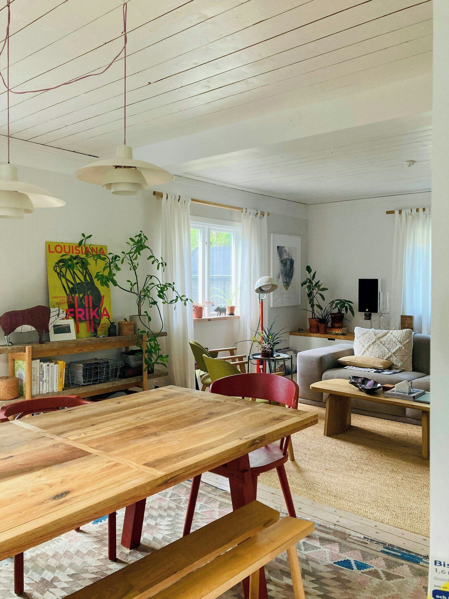A living room with a wooden table, red chairs, a sofa, and a bookshelf.