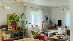 En stue med et træbord, røde stole, en sofa og en bogreol.