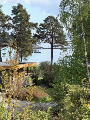 Ein Ufergrundstück mit Holzterrasse, Steg und einem Haus mit blauem Dach.