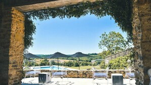 Uma área à beira da piscina com vista clara para a paisagem circundante, paredes de pedra e assentos externos.