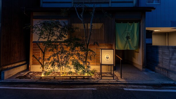 A building with a wooden facade, a tree in front, and a sign with Japanese characters.