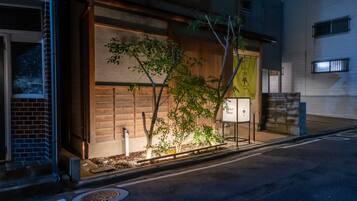 A hotel entrance with a wooden facade, a small tree, and a signboard.