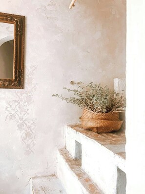 A rustic interior with a textured wall, a wooden-framed mirror, and a woven basket with dried plants on a white stone staircase. - Historic apartment with terrace in Suvereto (Suvereto)