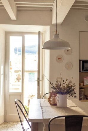 A dining area with a table, chairs, a hanging light fixture, a potted plant, and a door leading outside. - Historic apartment with terrace in Suvereto (Suvereto)
