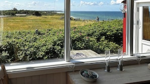 A room with a large window overlooking a grassy field and the sea. - Wooden house with panoramic view over Kattegat (Hundested)