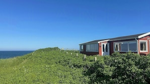 A red house with a white door and windows, surrounded by greenery and overlooking the sea. - Wooden house with panoramic view over Kattegat (Hundested)