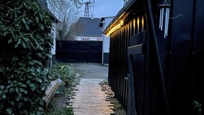 Uma trilha que leva a um edifício com exterior preto e fachada branca.