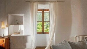 A room with a window, a wooden cabinet, a lamp, a radiator, and a couch. - 1700s design stone house in Mallorca with pool (Soller)