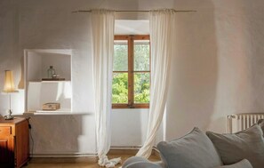 A room with a window, a wooden cabinet, a lamp, a radiator, and a couch. - 1700s design stone house in Mallorca with pool (Soller)