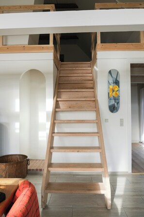 Eine Holztreppe in einem Raum mit weißen Wänden, einem Metalltopf und einem Skateboard an der Wand.