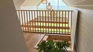 Un balcon agrémenté d’un pot de fleurs, doté d’une balustrade en bois et offrant une vue sur la plage.