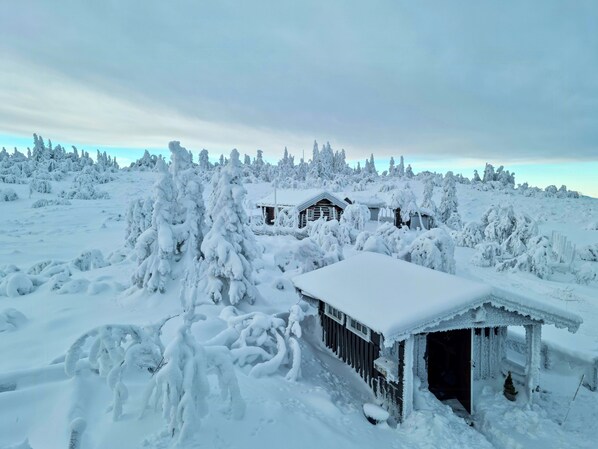 Un paysage enneigé avec une cabane en bois et un petit abri.