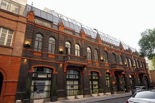 Een historisch gebouw met gebogen ramen, een balkon en een moderne glazen uitbouw.