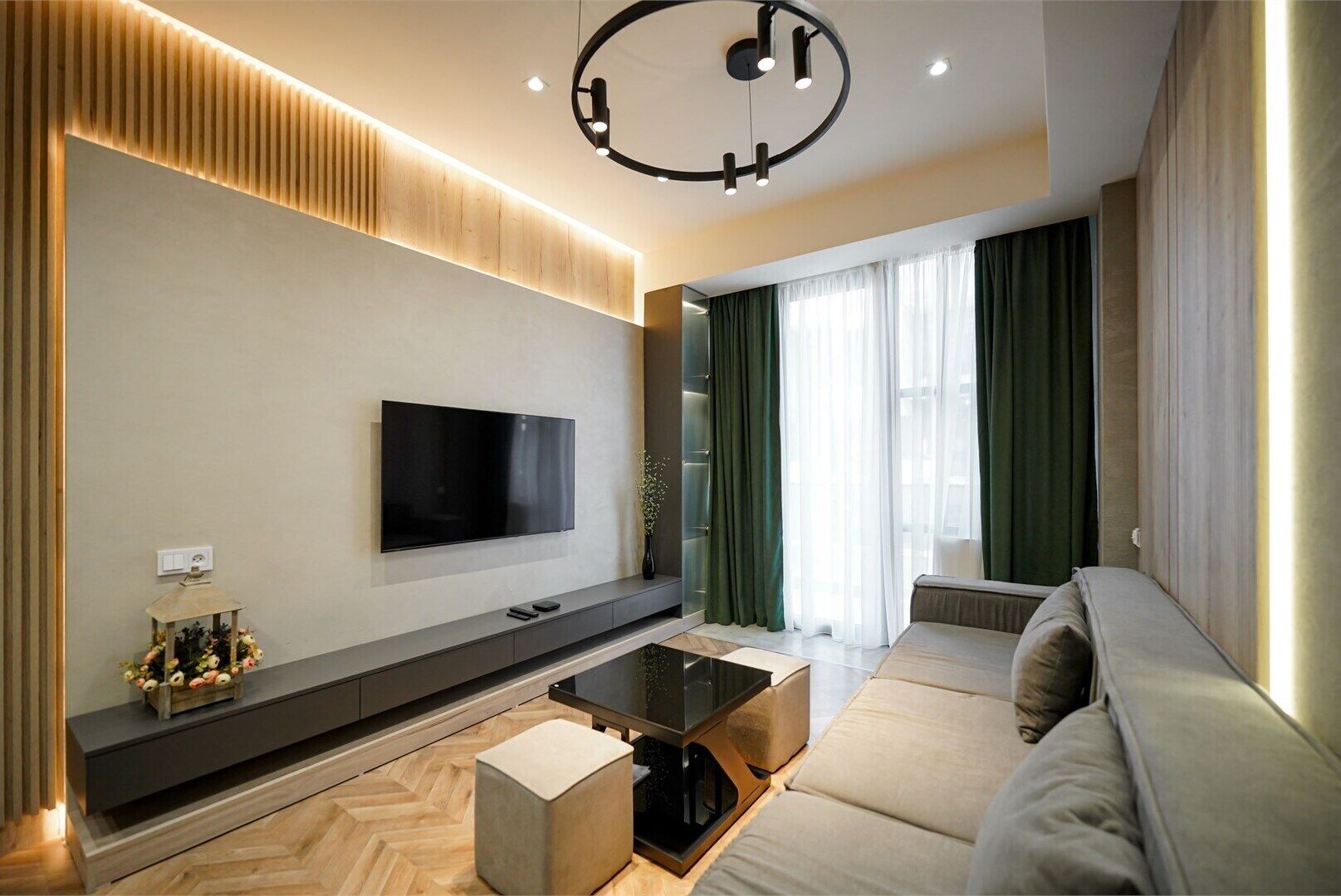 A modern living room with a flat-screen TV, a sofa, a coffee table, and a decorative lantern.