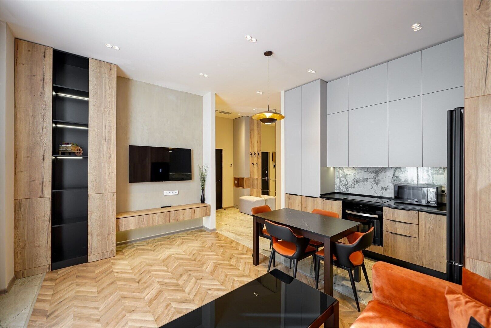 A modern kitchen with grey cabinets, a black countertop, and a built-in microwave.