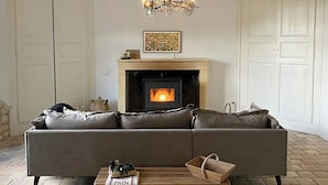 A living room with a fireplace, a sofa, a coffee table, and a chandelier. - Peaceful cottage near Saint-Savin Abbey (Journet)