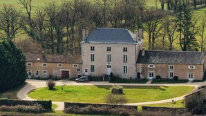 A large, multi-story building with a symmetrical facade, surrounded by a well-maintained lawn and a few trees. - Peaceful cottage near Saint-Savin Abbey (Journet)