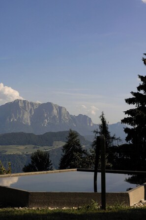 Un paisaje montañoso con cielo despejado, una piscina y una estructura de madera.