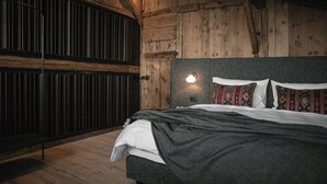 Una habitación con paneles de madera, una cama, una lámpara en la pared y un banco.
