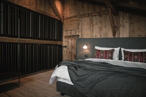 Una habitación con paneles de madera, una cama, una lámpara en la pared y un banco.