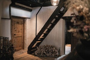 Una escalera de madera que conduce a un entrepiso con una puerta de madera y una pila de leña.