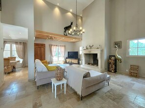 Ein geräumiges Wohnzimmer mit einer Couch, einem Fernseher, einem Kamin und einer Kandelaber.