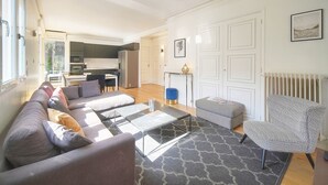 Ein modernes Wohnzimmer mit Sofa, Hocker, Couchtisch und einem gemusterten Teppich.