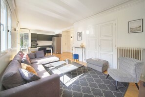 Ein modernes Wohnzimmer mit Sofa, Hocker, Couchtisch und einem gemusterten Teppich.
