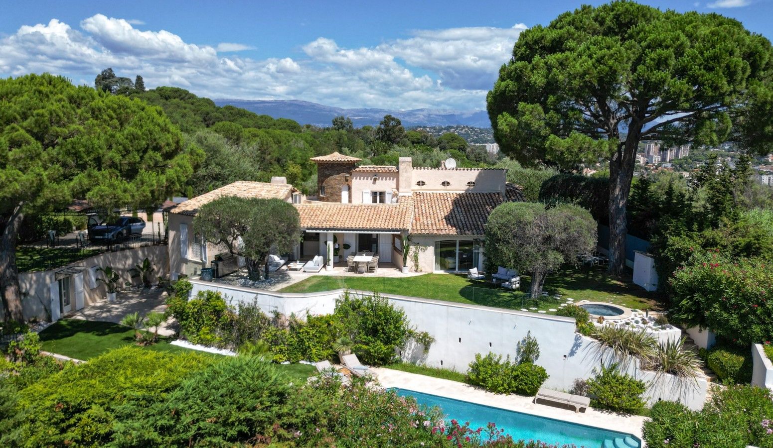 A large house with a swimming pool, surrounded by lush greenery and trees.