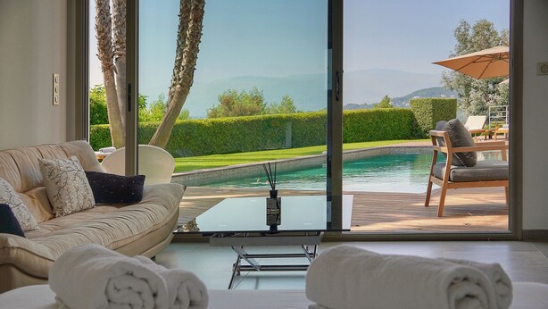 Ein Zimmer mit einer Couch, einem Tisch und Blick auf einen Pool und die Landschaft.