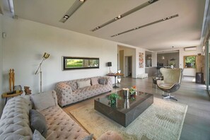 A modern living room with a sectional sofa, a glass coffee table, and a contemporary chair.